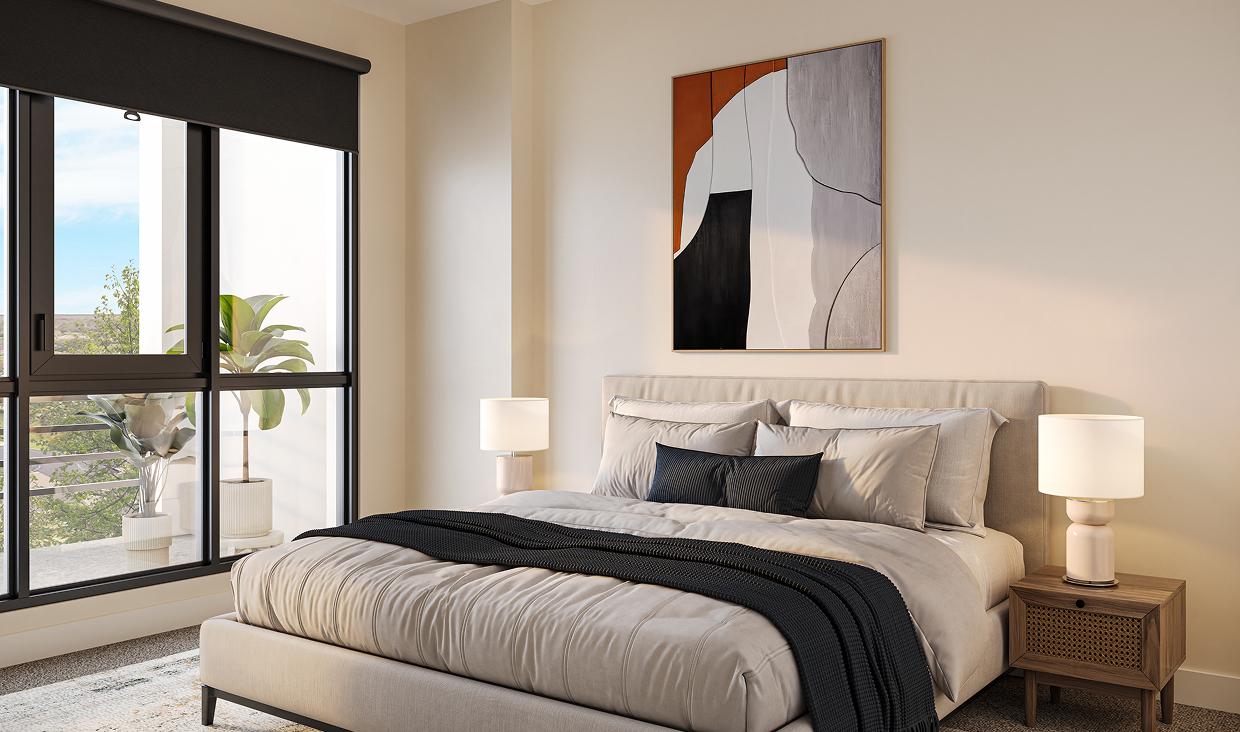 Bright bedroom with a large window, brown bed, neutral decor, and a modern round mirror above the headboard.