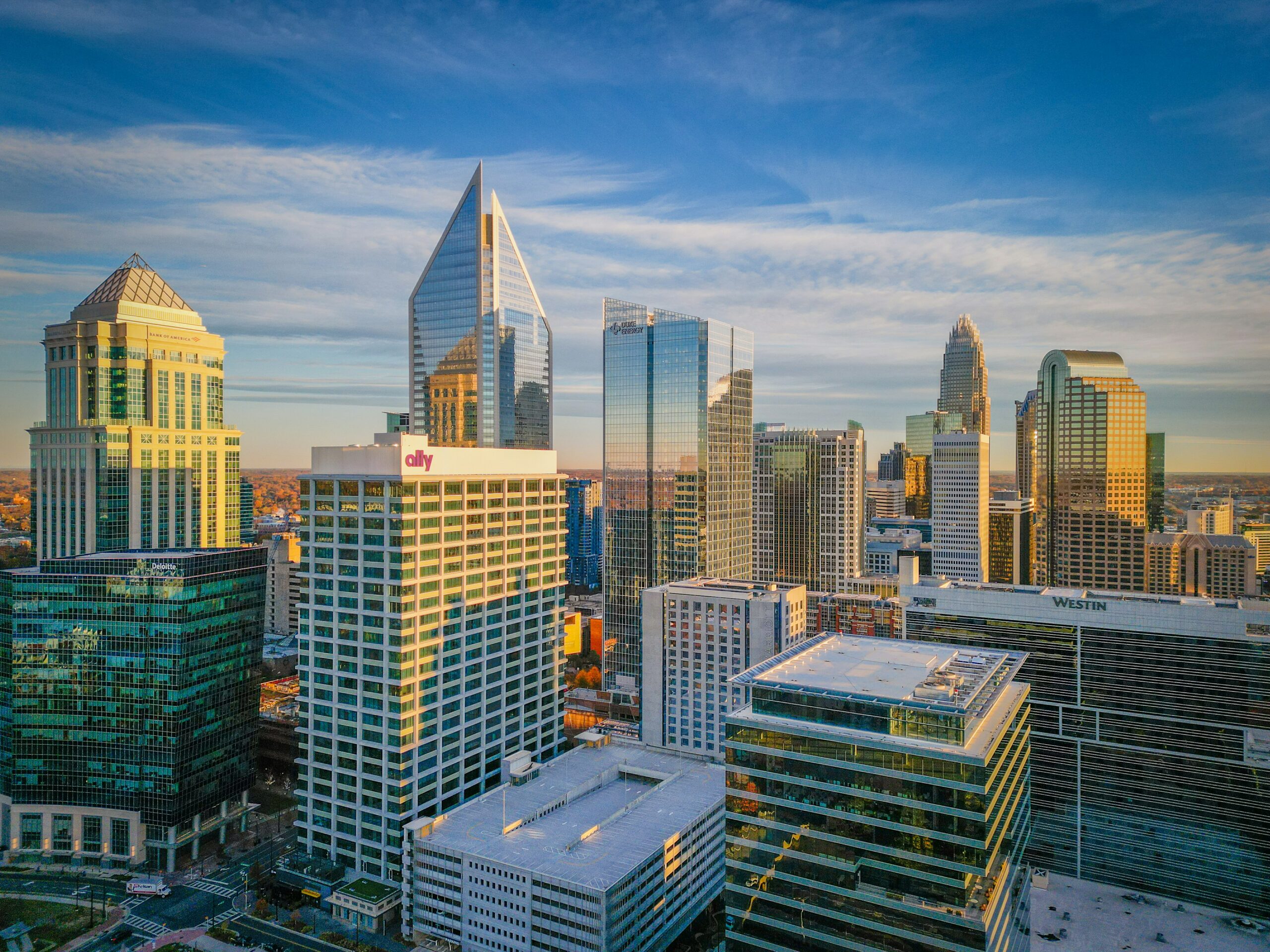 Aerial view of a city skyline with modern skyscrapers under a blue sky with scattered clouds.