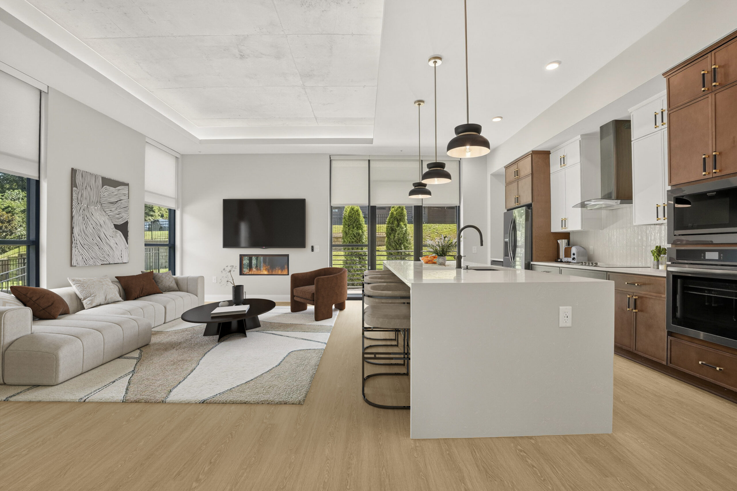 Modern open-plan living room with a white kitchen island, dining stools, and a seating area featuring a fireplace and television.