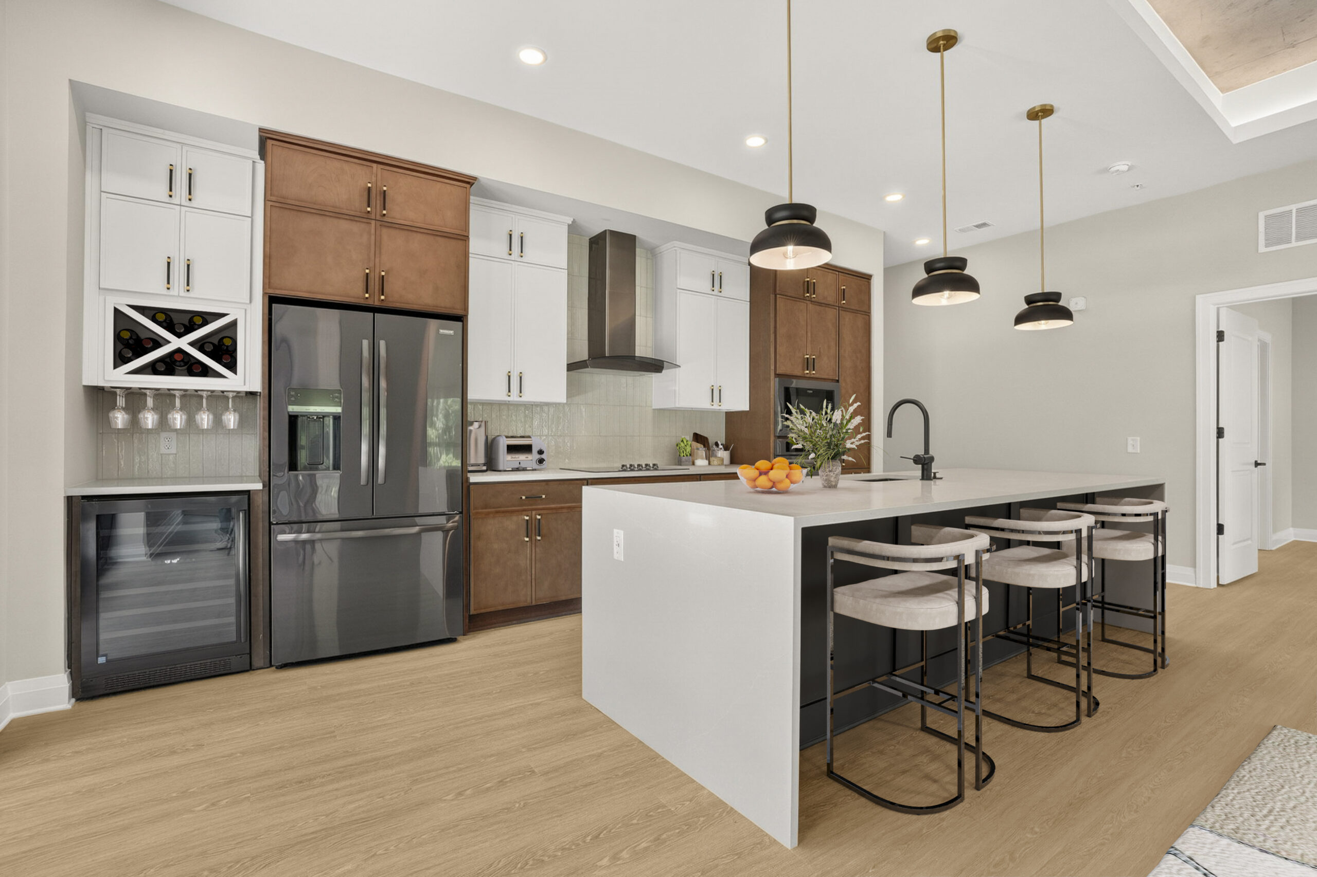 A modern kitchen with a large central island, white and wood cabinetry, and three pendant lights hanging above the breakfast bar.