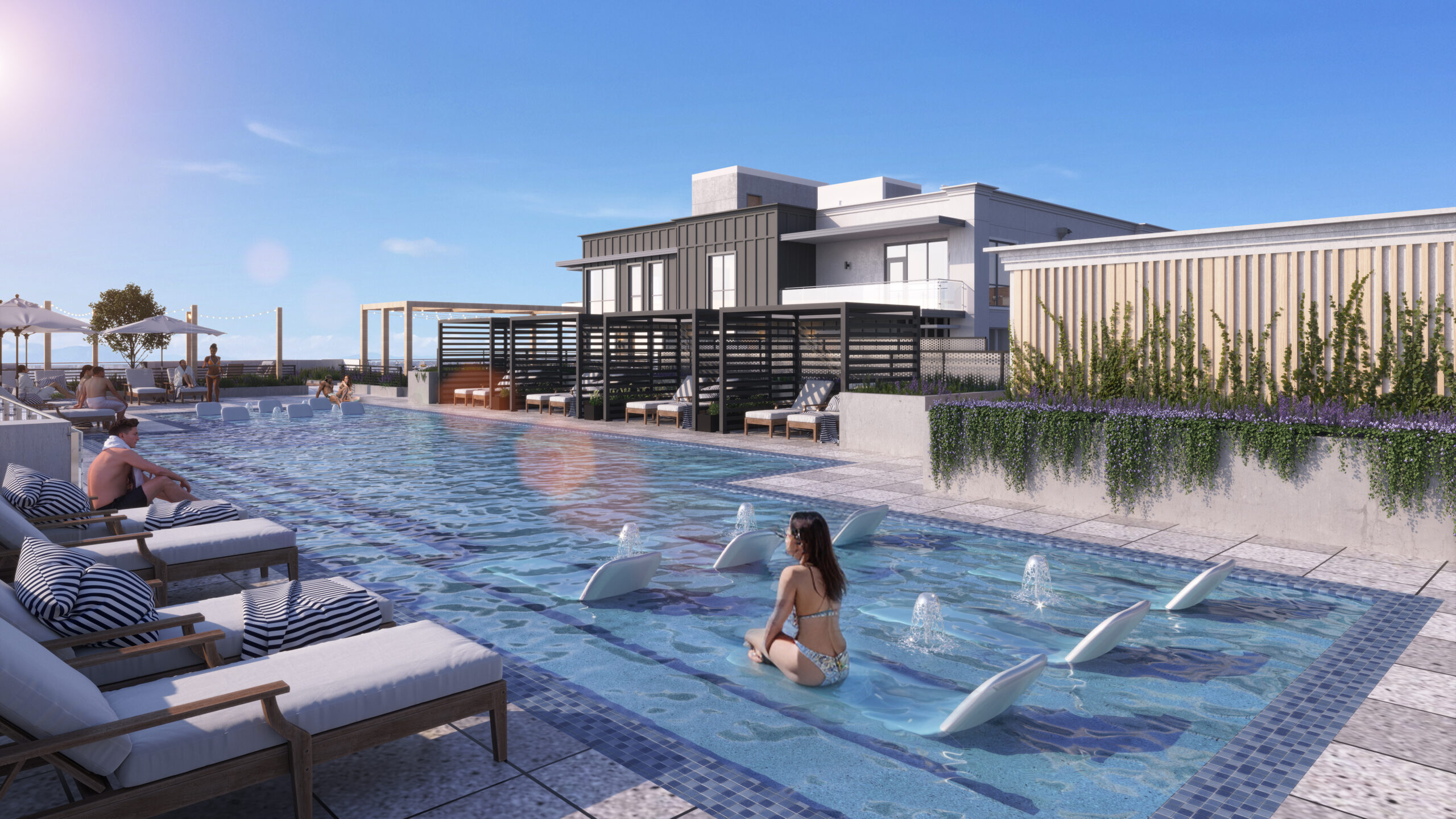 People relax on lounge chairs and in a modern rooftop pool with fountains, under a clear blue sky.