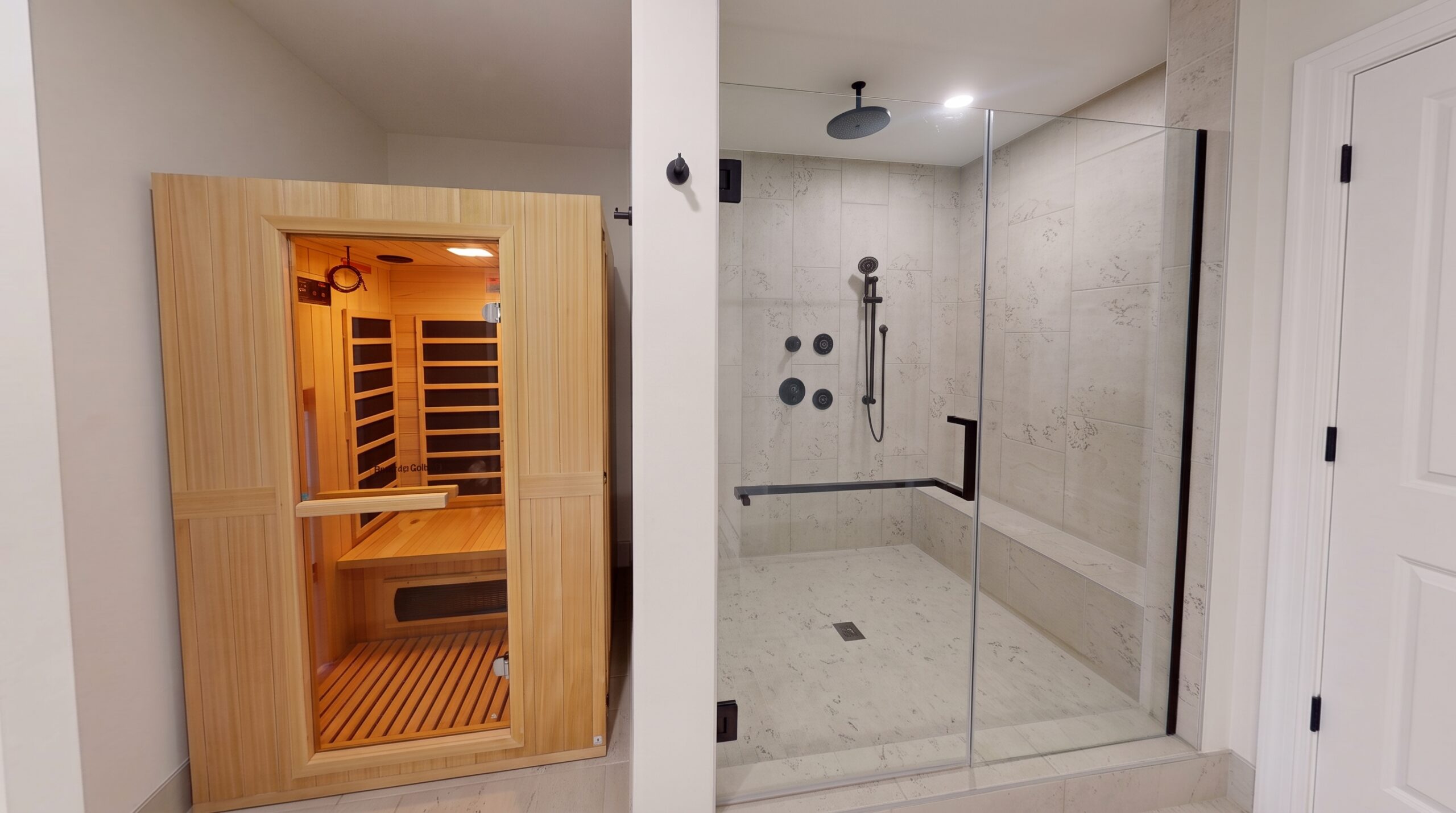 A wooden sauna cabin next to a glass-enclosed walk-in shower with stone tile walls.
