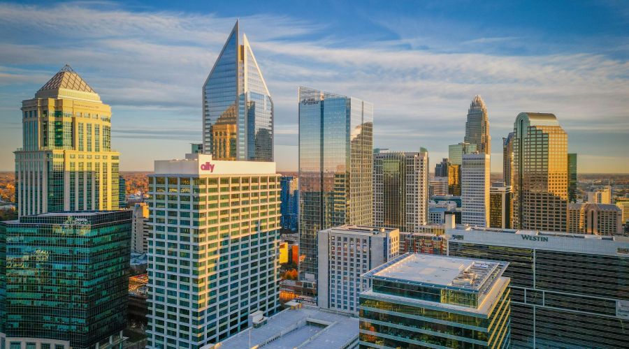 Aerial view of a city skyline with modern skyscrapers under a blue sky with scattered clouds.
