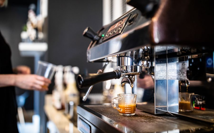 An espresso machine extracting a shot of coffee into a small glass cup.